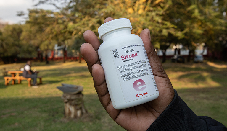 A woman holds an empty bottle of ARVs that came from a poultry farm in Harare, Zimbabwe. Some poultry farmers are mixing ARV’s with chicken feed to feed their chickens. Photography by Aaron Ufumeli/SAAJP
