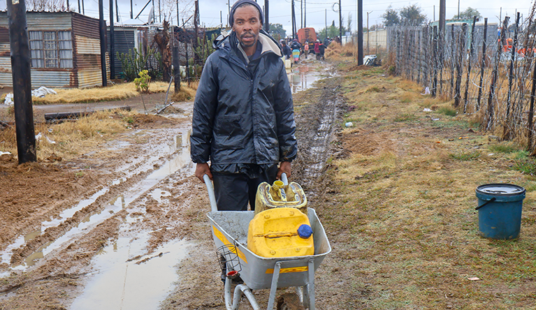 Residents push wheelbarrows carrying water containers through muddy streets in Mimosa Township in Delmas, as they search for water amid ongoing water shortages. Photograph: Rodney Hlatshwayo.